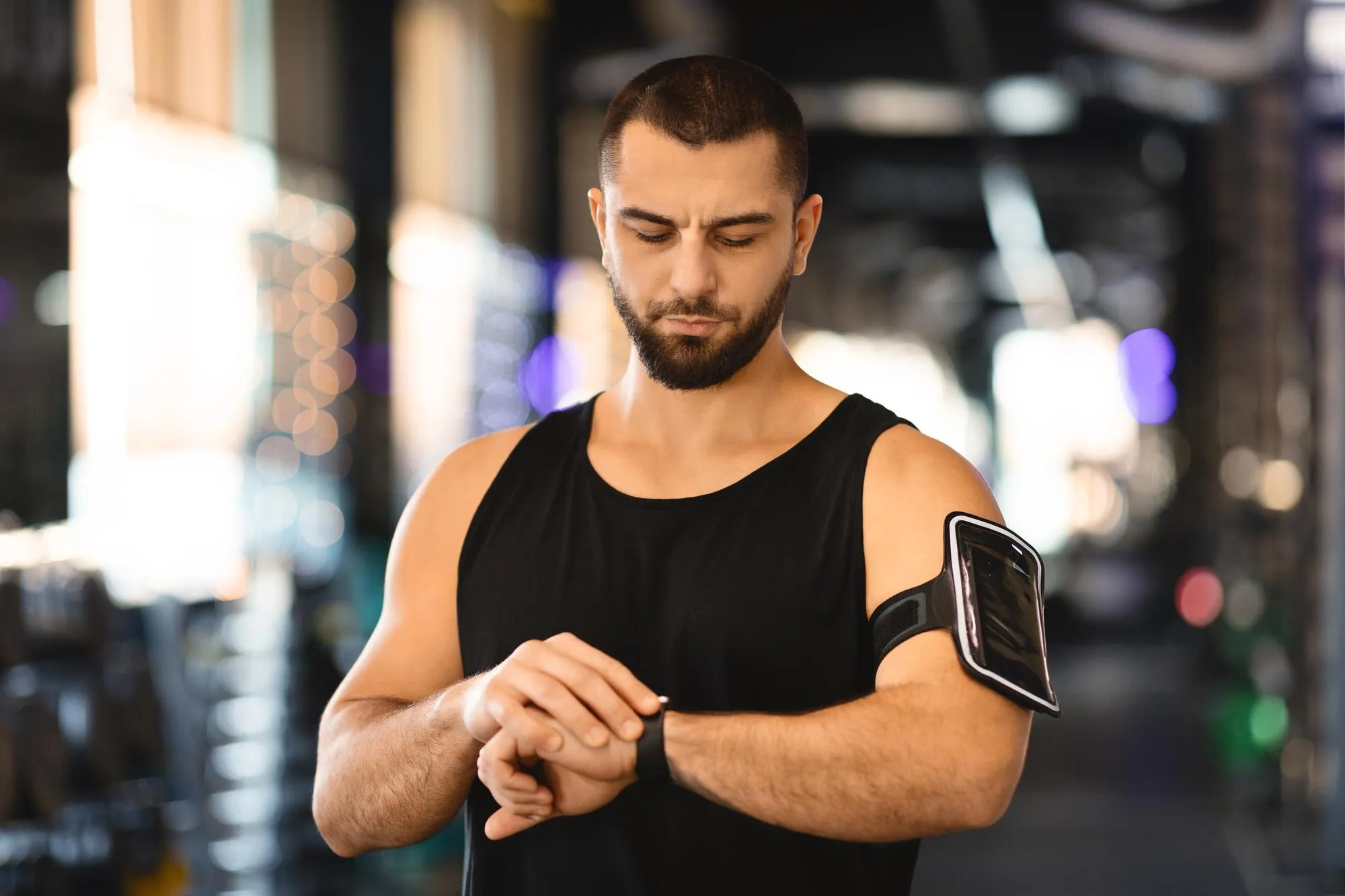 A man in a gym checking a fitness tracker on his wrist