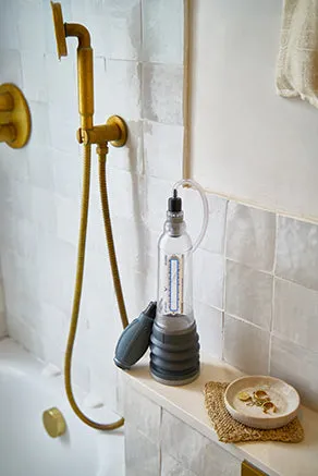 A VaxAid vacuum pump cylinder and hand bulb standing on a bathroom shelf